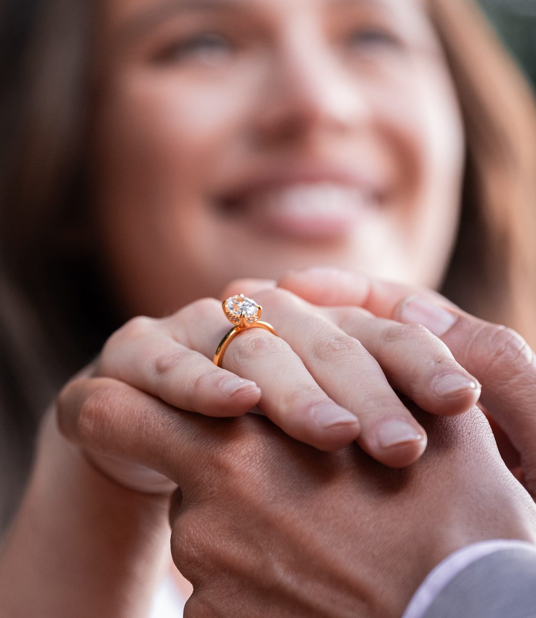 A smiling woman holding hands with her partner, wearing a display ring